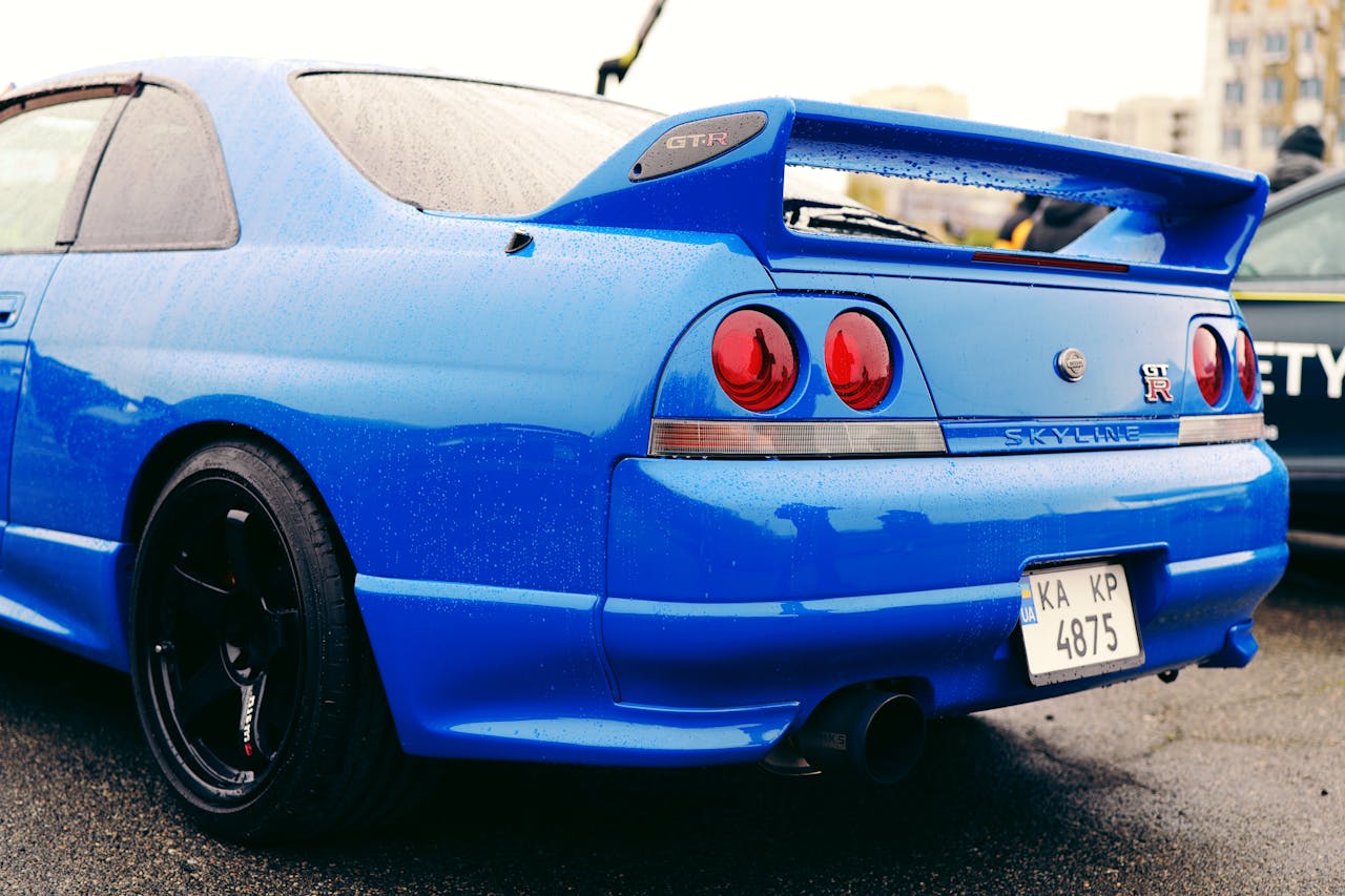 Blue Nissan Skyline GT-R parked at a car show in Ukraine, featuring iconic design and wet surface reflections.