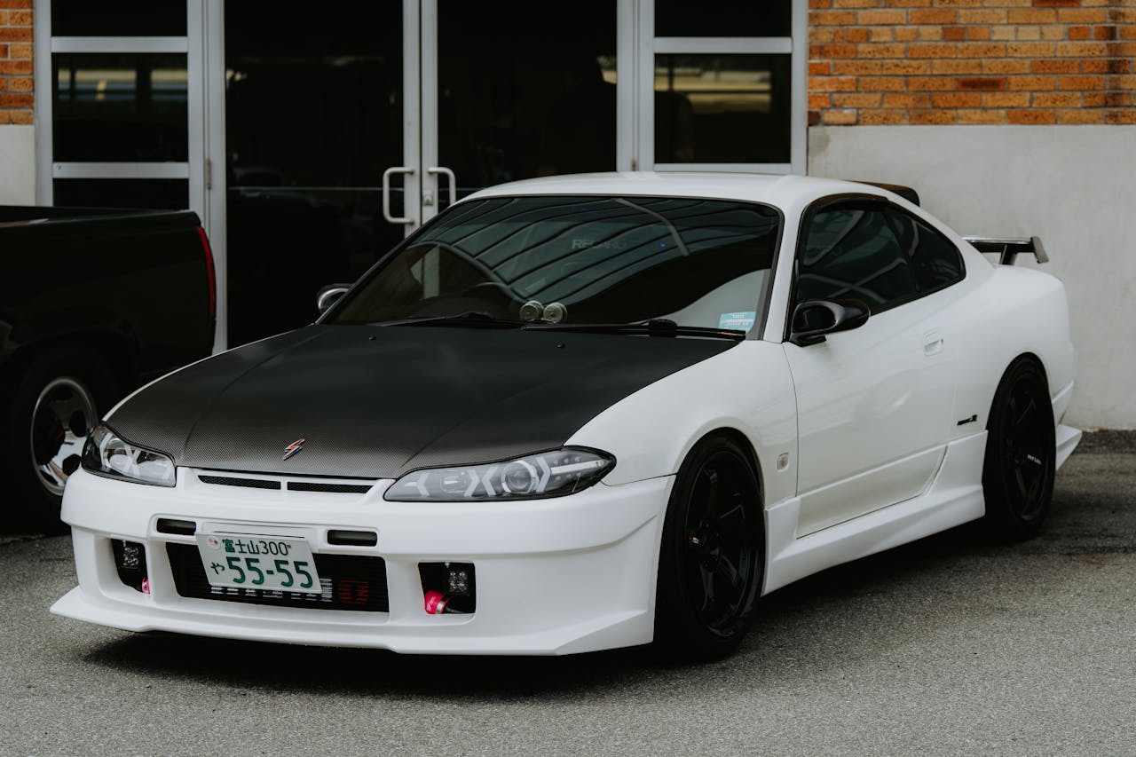 High-performance white sports car with a black hood parked outside a building.