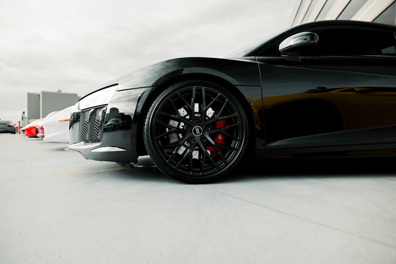 Close-up of a black luxury sports cars wheel detail in an outdoor setting.
